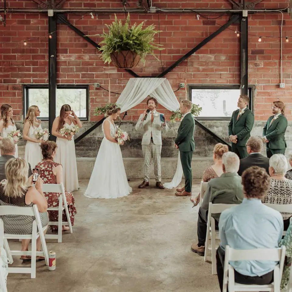 Wedding party and pastor during ceremony while guest look on inside of City House