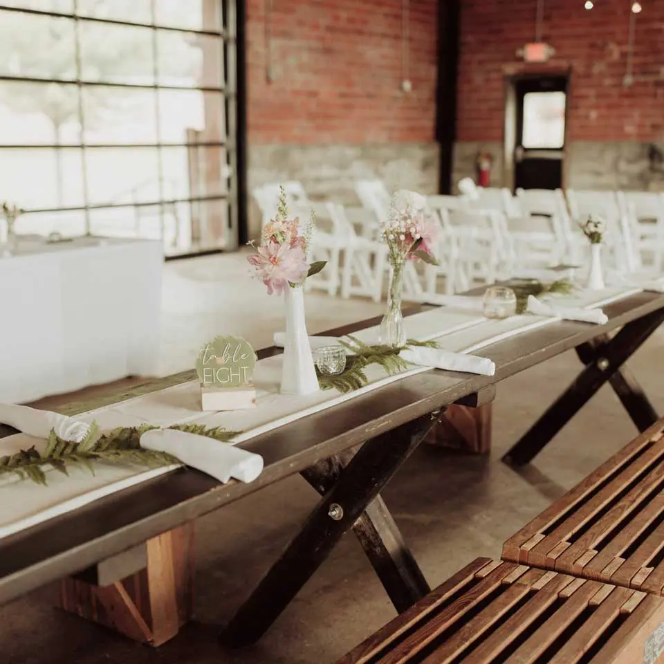 Wooden table and bench with floral arrangements and table setting
