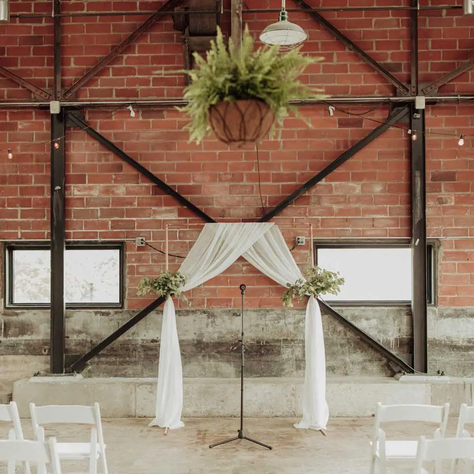 Wedding altar setup with white linen and microphone against a brick wall