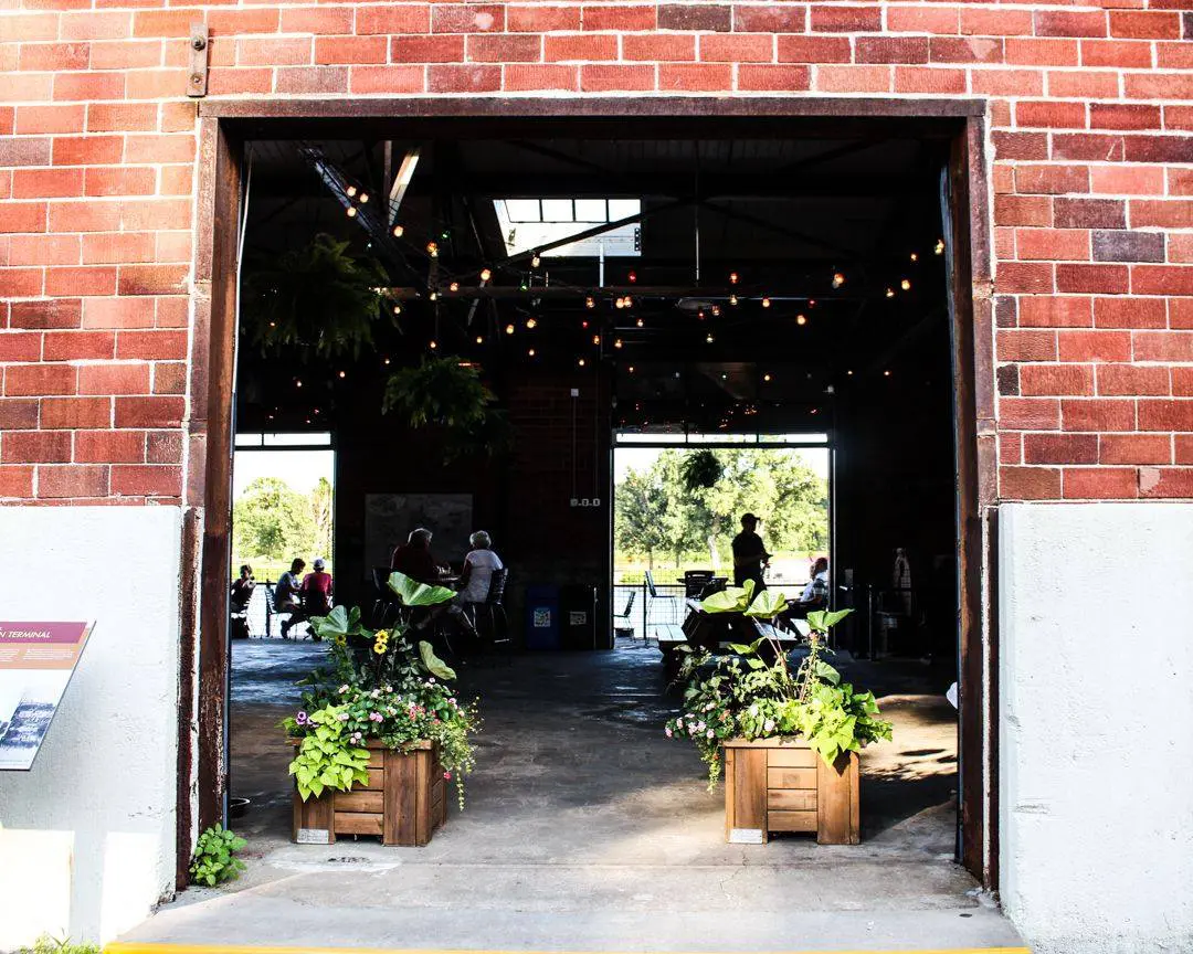 Open air door of City House with planters. In the background are patrons inside of building.